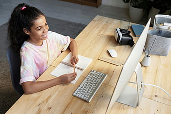 girl in pink t-shirt, looking at iMac, young girl smiling, studying online, home study, computer use, taking notes, online learning, home desk, virtual reality headset, girl studying