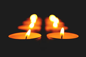 candles, illuminated, black background, warm glow, dark setting, serene, lit candles, close-up, row of candles, candlelight, ambiance