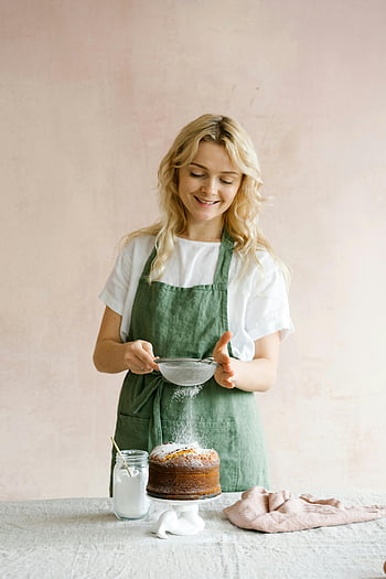 donna, aspersione, zucchero a velo, torta al forno, sorridente, grembiule, decora, dolce tocco finale, decorazione della torta, cottura al forno