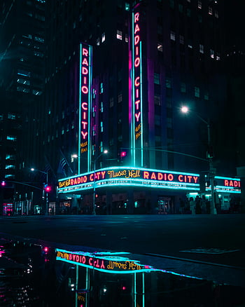 Radio City Music Hall, nighttime view, neon lights, vibrant scene, reflections, New York City, iconic landmark, urban nightlife, theater exterior, cityscape, night photography