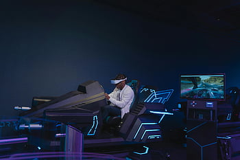 virtual reality, VR headset, driving simulation, young man, indoor gaming, immersive experience, virtual reality glasses, gaming setup, futuristic design, interactive technology, entertainment technology