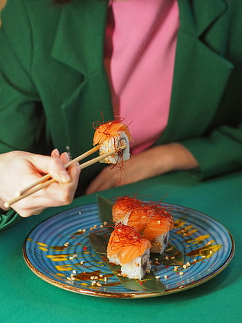 sushi, chopsticks, green jacket, colorful plate, eating sushi, person eating, food photography, Japanese cuisine, dining, meal, table setting