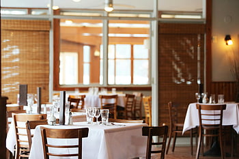 interiér restaurace, dřevěné židle, dřevěné stoly, jídelní nastavení, čiré sklenice na víno, klidná atmosféra, nastavení tabulky, restaurace tabulky, jídelna, bílý ubrus, skleněné zboží