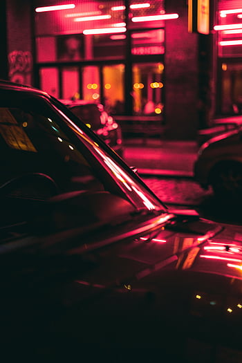 red car, night time, urban street, neon lights, car reflections, vibrant city, night scene, street illumination, car lights, city nightlife, night photography
