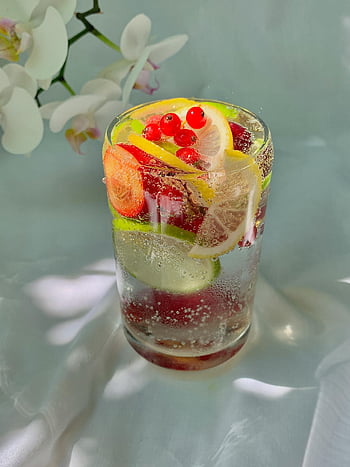 citrus drink, red berries, sparkling water, summer refreshment, vibrant glass, berry-infused, lemon slices, lime slices, refreshing beverage, fruit-infused water, citrus and berry