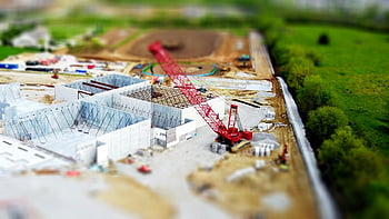 tilt shift lens, red crane, miniature photography, construction site, aerial view, green fields, concrete buildings, miniature effect, construction crane, tilt shift, miniature scene