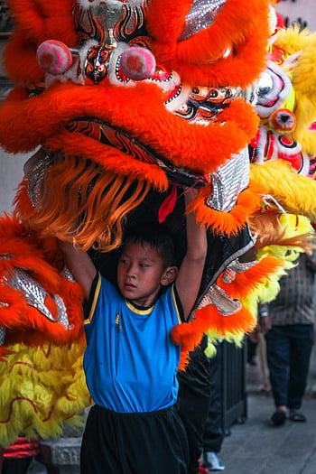 dragon dance, young boy, traditional Chinese, festival parade, vibrant outdoor, lion dance, cultural performance, festive event, colorful costumes, cultural tradition, Chinese celebration