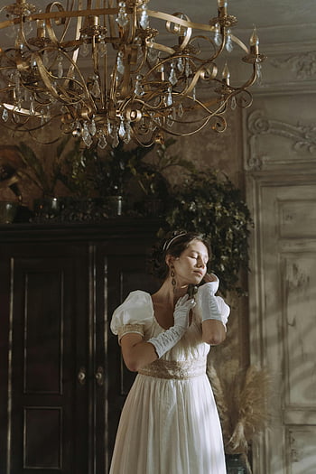 white dress, opera gloves, chandelier, vintage room, woman standing, elegant attire, vintage style, indoor setting, graceful pose, ornate chandelier, classic fashion