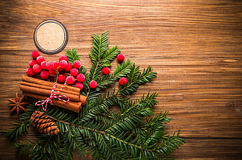 holiday-themed flat lay, festive decorations, pine cones, berries, wooden background, green leafed wall decor, cinnamon sticks, star anise, Christmas decorations, flat lay photography, holiday decor