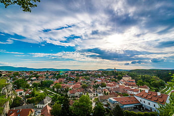 aerial view, picturesque village, red-roofed houses, dramatic sky, scenic landscape, town near forest, countryside scenery, rural town, natural beauty, European village, sunny day