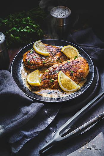 roasted chicken, lemon slices, chicken breast, dark plate, fresh lemon, delicious chicken, roasted chicken breast, garnished chicken, dark background, food photography, savory dish