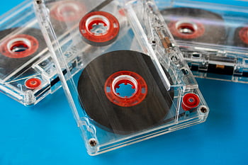 transparent audio cassettes, red reels, blue background, vintage cassettes, close-up, selective focus, compact cassettes, visible tape, retro audio, music storage, audio media