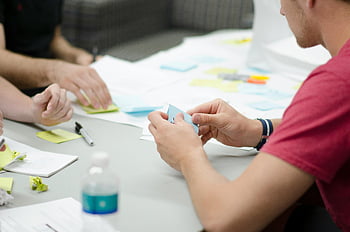 collaborative workspace, brainstorming, sticky notes, teamwork, planning, blue sticky notes, people working, office environment, creative meeting, group discussion, project planning