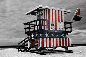 lifeguard tower, stars and stripes, sandy beach, patriotic themes, red and blue striped, beach safety, American flag design, beach lifeguard, beach structure, beach photography, beach scenery