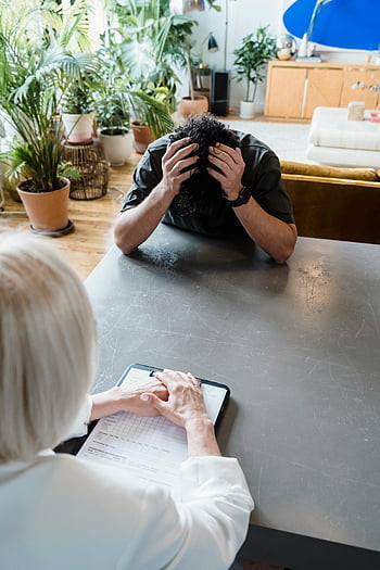 emotionaler Patient, Kopf halten, Delanner Mann, Indoor-Psychotherapie, Therapeutenberatung, Psychische Gesundheit, Therapiesitzung, emotionale Not, Beratung, geistiges Wohlbefinden, Innenumgebung