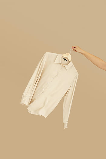 Beżowa koszula, ustawienie minimalistyczne, wieszak ręczny, Białe polo długie rękawy, Prosta koszula, beżowym tle, moda minimalistyczna, casualowy strój, Koszulka z długim rękawem, minimalistyczny styl, Wyświetlacz wieszaka