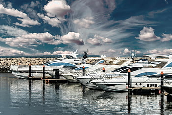 white yachts, scenic marina, dramatic cloudy sky, calm waters, yacht reflection, elegant yachts, docked yachts, marina view, luxury boats, serene waters, yacht marina
