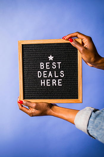 letter board, best deals here, hands holding, blue background, promotional sign, deal advertisement, black letterboard, wooden frame, red nails, casual attire, marketing display