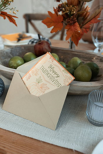 Happy Thanksgiving, greeting card, brown envelope, autumn fruits, festive table setting, fall decor, Thanksgiving card, seasonal table, harvest theme, autumn leaves, limes