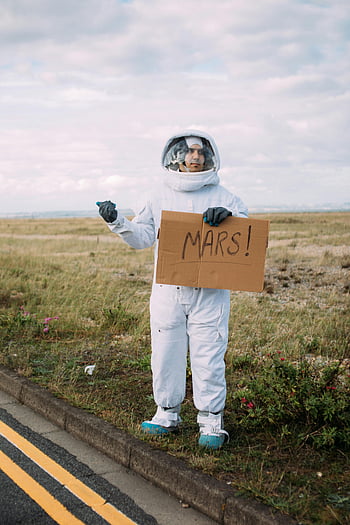 宇宙服、 ヒッチハイク、 火星のサイン、 人けのない道、 宇宙飛行士、 段ボールの看板、 屋外のシーン、 未来的な、 旅行のコンセプト、 SF、 ロードトリップ