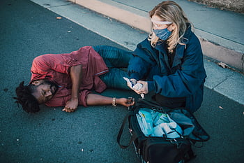 paramedic, helping, injured man, lying on ground, roadside, first aid, medical assistance, emergency response, paramedic equipment, outdoor scene, accident site