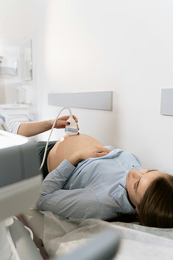 pregnant woman, ultrasound scan, clinic setting, medical examination, prenatal care, healthcare professional, medical equipment, fetal development, expectant mother, medical sonography, health care