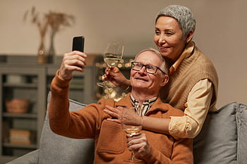 senior couple, taking selfie, happy couple, enjoying wine, indoor photo, memorable moment, senior selfie, wine glasses, cozy setting, elderly couple, home setting
