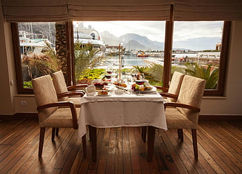 přímořská restaurace, marina pohled, gurmánská jídla, dobré jídlo, elegantně nastavená tabulka, červené víno, čiré sklenice na víno, jídelní nastavení, V nábřeží, interiér restaurace, dřevěná podlaha