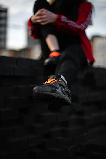 Czarny Nike Air Huarache, Pomarańczowe koronki, miejskie ustawienie, swobodna odzież uliczna, czarne trampki, zbliżenie, Stylowe trampki, moda miejska, styl uliczny, trampki nike, czarne buty