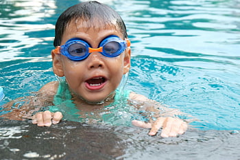 toddler swimming, pool, blue goggles, young child, playing in water, enjoying water, swimming pool, child in pool, water activity, summer fun, kids swimming