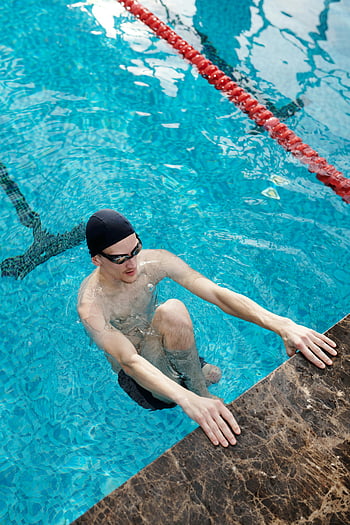 uomo a bordo piscina, nuotatore maschio adulto, piscina coperta azzurra limpida, nuotatore che si prepara, bordo piscina, piscina al coperto, nuotatore, nuoto, piscina, cuffia da nuoto, occhiali
