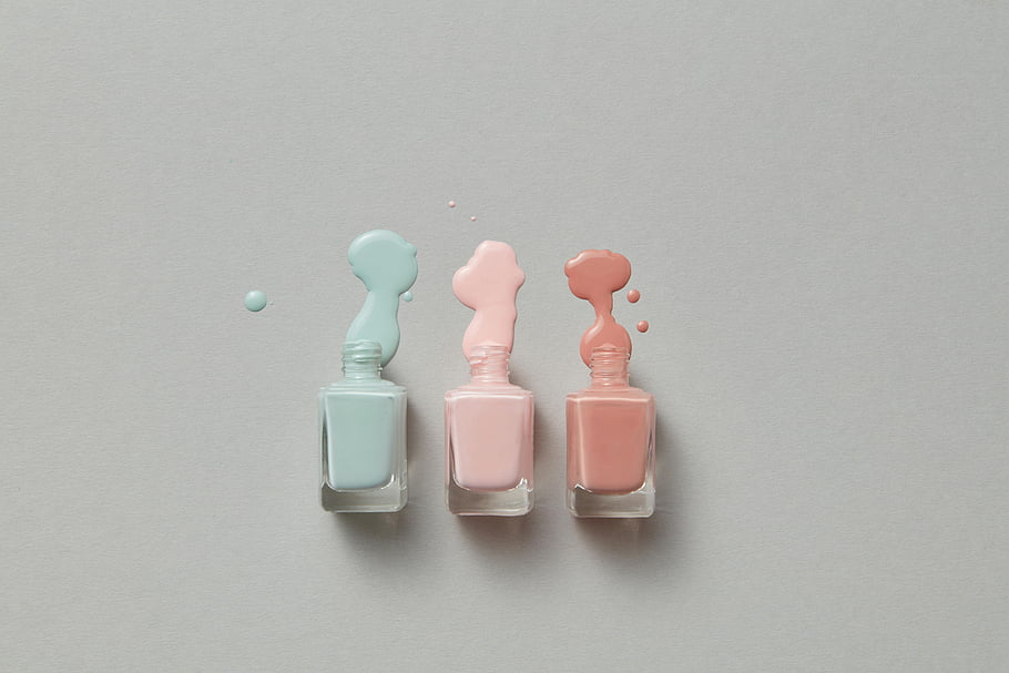 pastel nail polish, vibrant spills, gray background, clear glass bottles, nail polish bottles, pastel colors, nail polish spills, beauty products, cosmetic photography, minimalistic design, pastel aesthetics