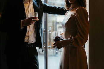 茶色のコートの女性、 透明なコップを持つ、 洗練されたカップル、 フォーマルな服装、 雰囲気のあるレストラン、 飲み物、 エレガントな設定、 屋内シーン、 スタイリッシュな衣装、 懇親会、 夕方の雰囲気