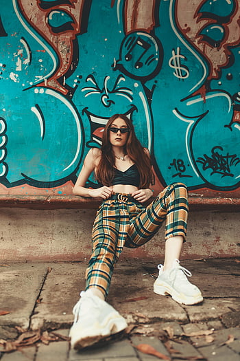 nő, graffiti fal, kockás nadrág, divatba jövő, magabiztos póz, élénk graffiti, városi stílus, napszemüveg, fehér cipők, utcai divat, csípő divat