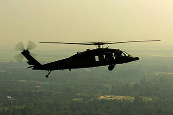 helicopter silhouette, green landscape, twilight, black helicopter, green leaved trees, stillness moment, aerial view, military helicopter, natural scenery, outdoor scene, flight over trees