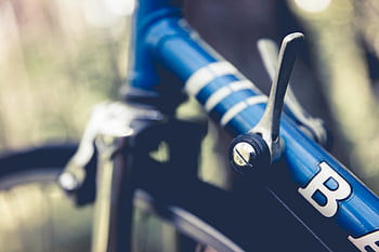 blue bicycle, black handlebar, gear lever, top tube, close-up, blurred background, bike details, cycling equipment, outdoor cycling, bicycle components, blue bike