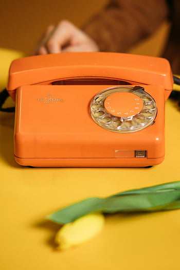 orange vintage telephone, yellow table, rotary dial, bright orange, vintage phone, yellow background, retro phone, classic telephone, old-fashioned phone, vintage communication, orange phone