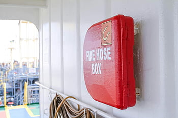 red fire hose box, ship deck, safety equipment, close-up photo, bright red, fire safety, maritime safety, emergency equipment, ship safety, hose box, fire hose