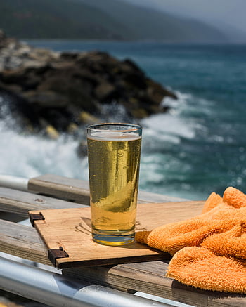 tiszta pohár, sárga folyadék, barna fa daraboló deszka, hűtött lager, faasztal, óceáni kilátás, nyári kikapcsolódás, strand jelenet, kültéri beállítás, frissítő ital, part menti légkör