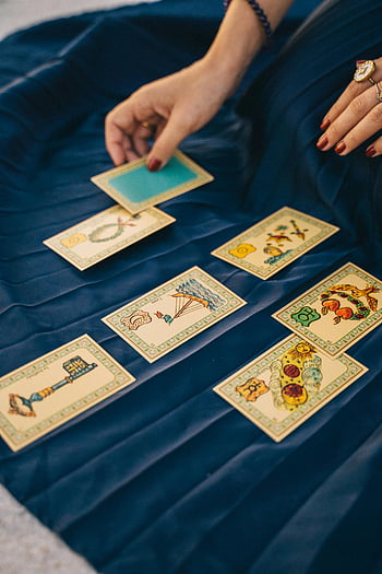 tarot cards, blue textile, card selection, close-up photo, hand selecting card, spread cards, blue cloth, white and yellow cards, divination, fortune telling, card reading