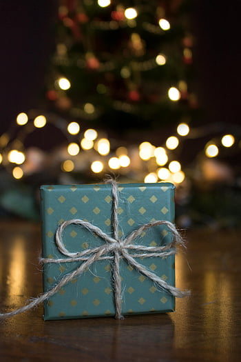 Yılbaşı hediyesi, Yeşil Hediye Kutusu, kahverengi ahşap yüzey, Sıcak bokeh ışıkları, dekore edilmiş hediye, yay, Noel ağacı, tatil dekoru, şenlikli, yakın çekim fotoğraf, hediye sarma