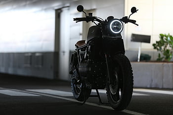 cafe racer motorcycle, parked motorcycle, indoor motorcycle, strong lighting contrast, sleek motorcycle, close-up photography, indoor parking, motorcycle details, modern motorcycle, urban motorcycle, motorcycle design