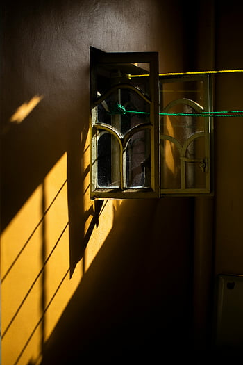 white framed glass window, yellow wall, warm sunlight, dramatic shadows, vintage window, bright yellow wall, interior lighting, architectural details, natural light, shadow play, window design