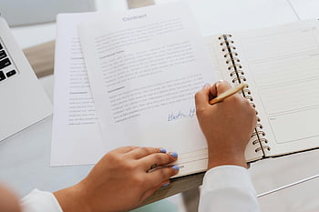 contract signing, hands signing, legal agreements, office supplies, desk, close-up, business documents, pen, notebook, laptop, paperwork