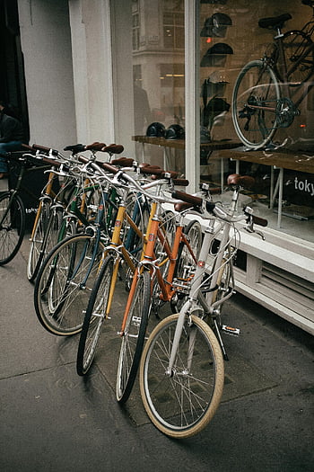 city bikes, parked bicycles, glass window, urban transportation, London shop, vibrant display, white and brown bikes, outdoor bicycles, city transportation, bike shop, urban bikes