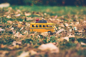 żółta zabawka autobus, Miniaturowy autobus zabawkowy, jesienne liście, trawa, bagaż na górze, zdjęcie zbliżenie, scena plenerowa, jesień, pojazd zabawkowy, żółta zabawka, Miniaturowy autobus