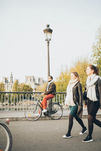 via della città, ciclista, pedoni, scenico all'aperto, lampione, donne che camminano, uomo in sella alla bici, contesto urbano, ponte, alberi, edifici