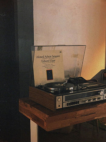 vinylový gramofon, Útulná vnitřní scéna, přehrávač vintage, hraní vinylového alba, dřevěný stůl, teplé osvětlení, hudební album, Ahmed Adnan Saygun, Edward Elgar, gramofonu, Retro zvukové vybavení
