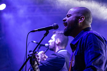 man singing, microphone, live performance, vibrant lighting, dynamic expressions, talented musicians, stage, concert, performance art, music event, live music
