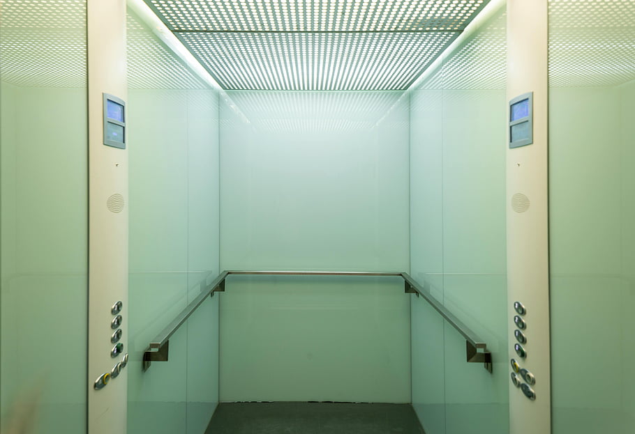 Kabina výtahu, prázdný výtah, minimalistický interiér, měkké osvětlení, Čistý výtah, Moderní výtah, Interiér výtahu, Design výtahu, tlačítka výtahu, kolejnice výtahu, strop výtahu